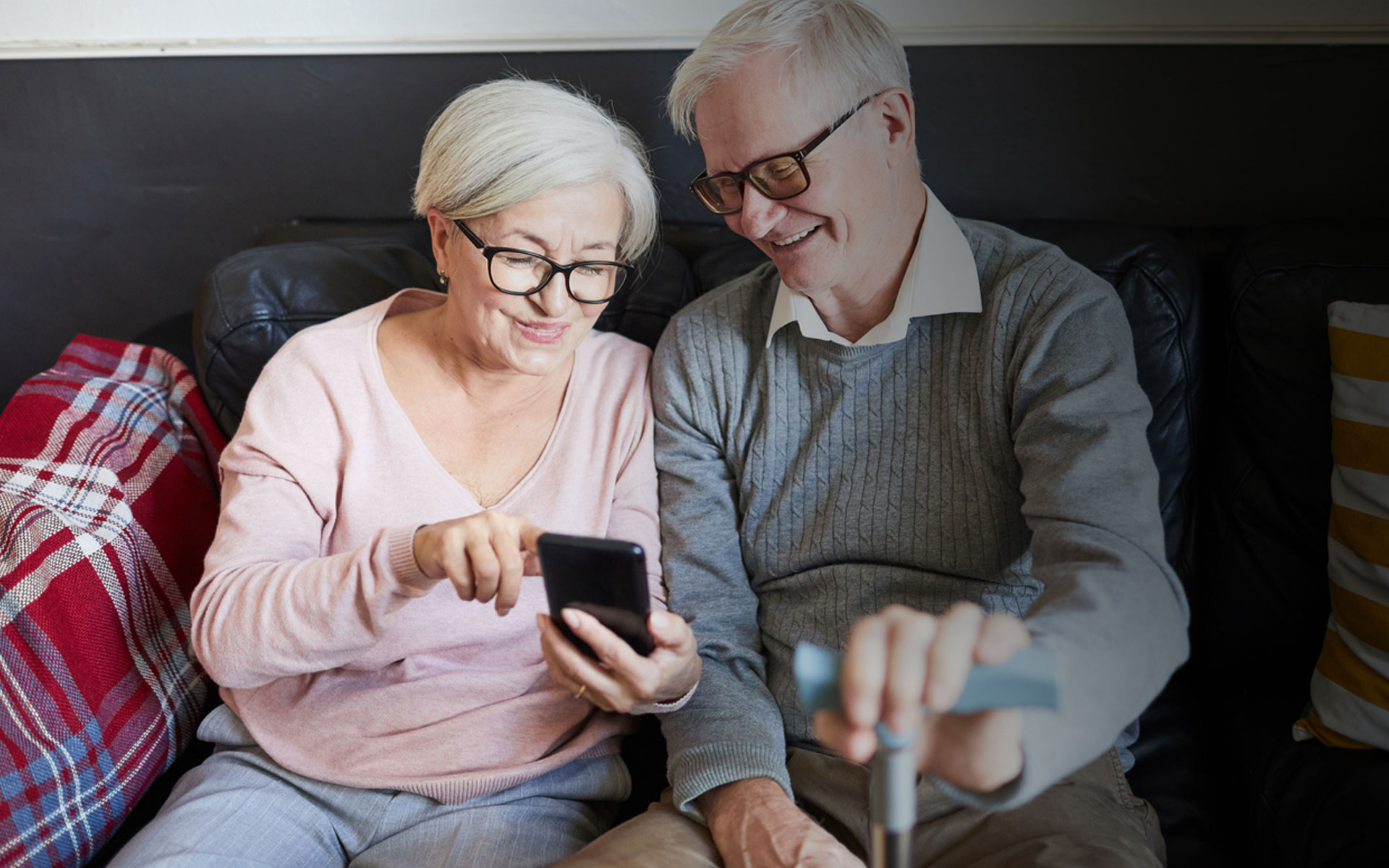Older couple sitting on couch, looking at phone