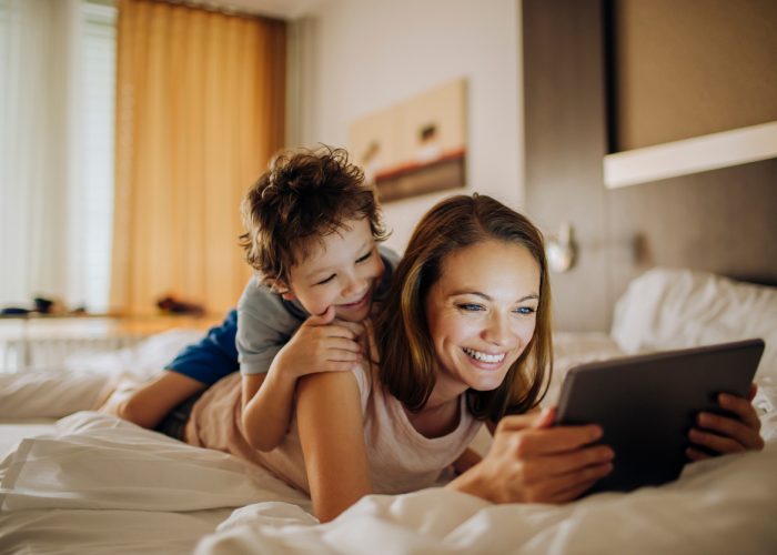 Mother and son play on tablet in hotel room