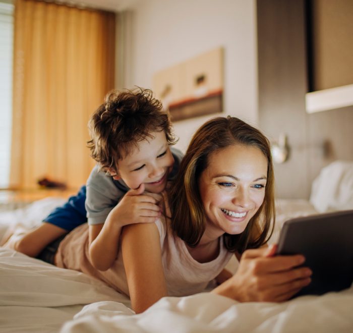 Mother and son play on tablet in hotel room