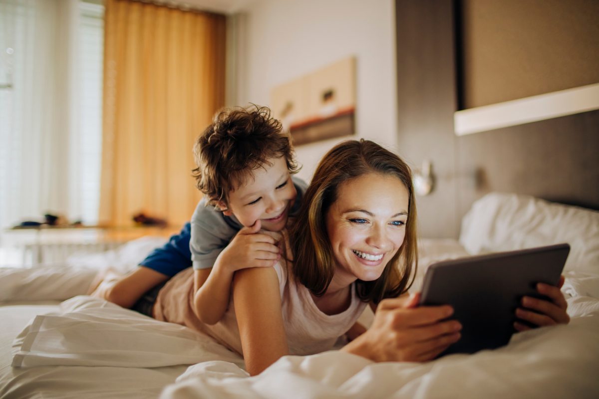Mother and son play on tablet in hotel room